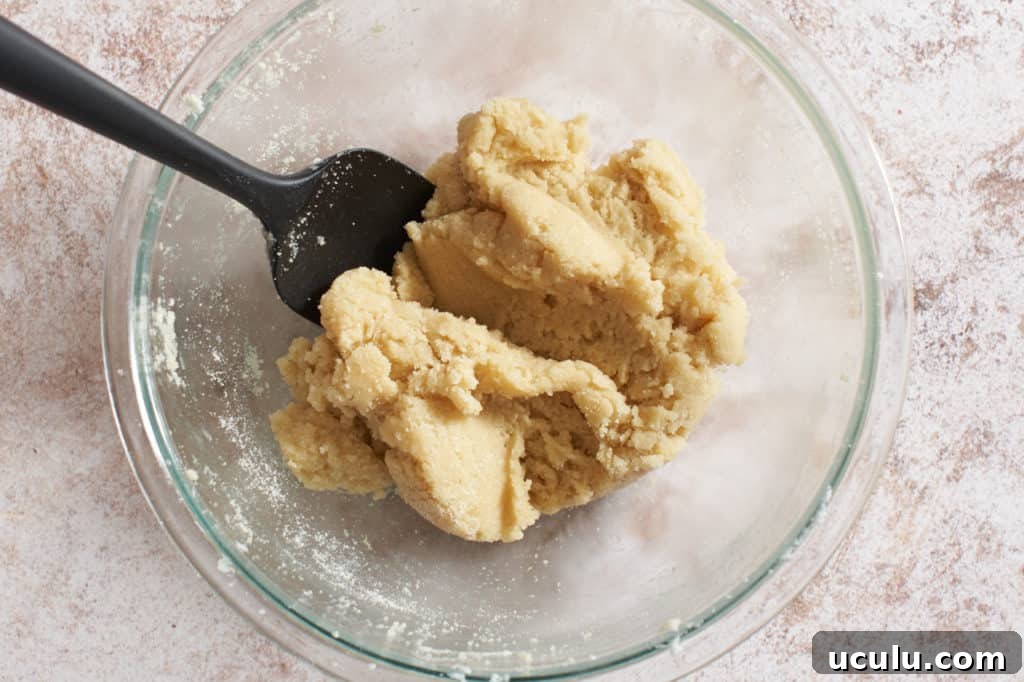 Finished amaretti dough in a bowl with a spatula.