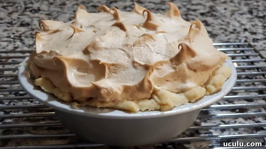 baked lemon meringue pie cooling on a rack.