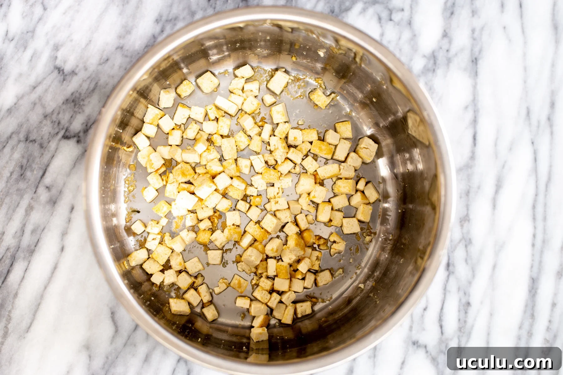 tofu cubes being fried in a pot