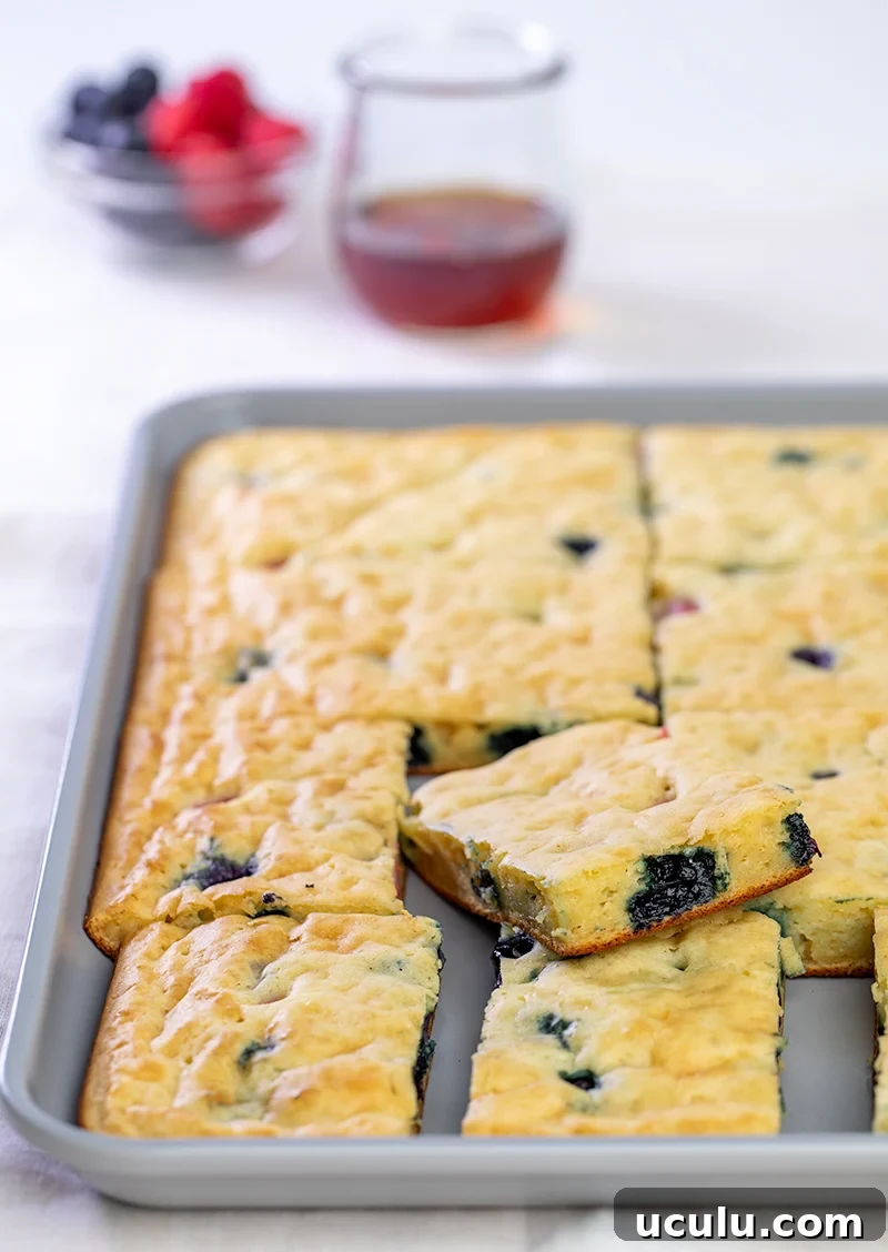 Sheet pan pancakes with blueberries sliced in gray pan