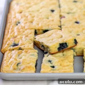 cut squares of pancakes with blueberries in gray sheet pan