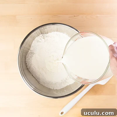 Pouring milk from measuring cup into pancake dry mix in bowl
