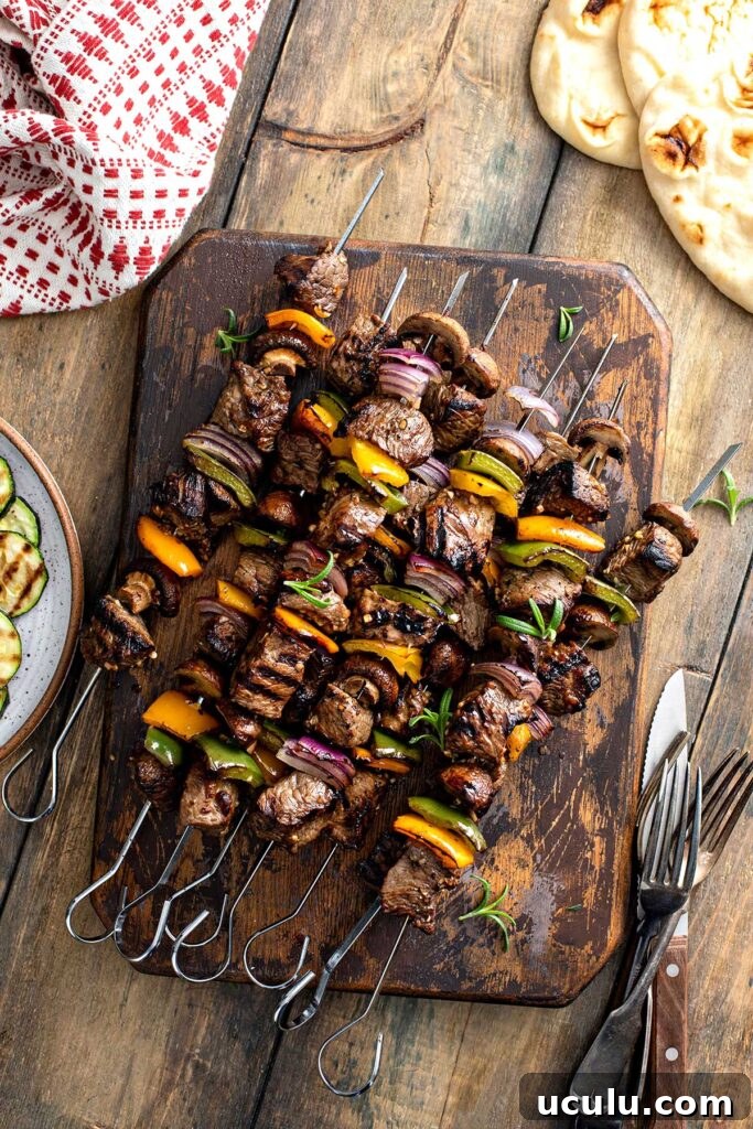 Grilled beef steak and veggies kabobs on a wooden board