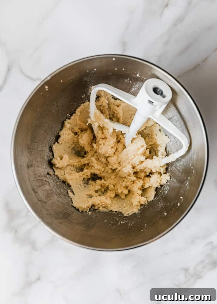 A silver bowl of creamed butter and sugar on a marble counter.