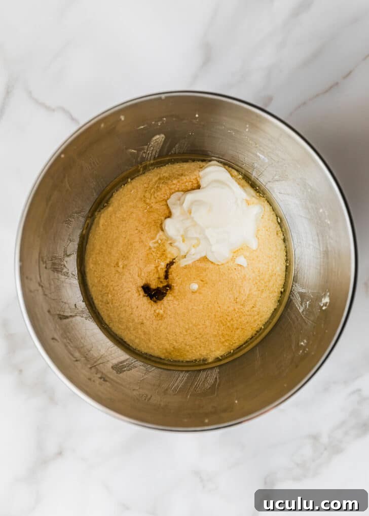 A silver bowl of butter, sugar, eggs, and sour cream on a marble table.
