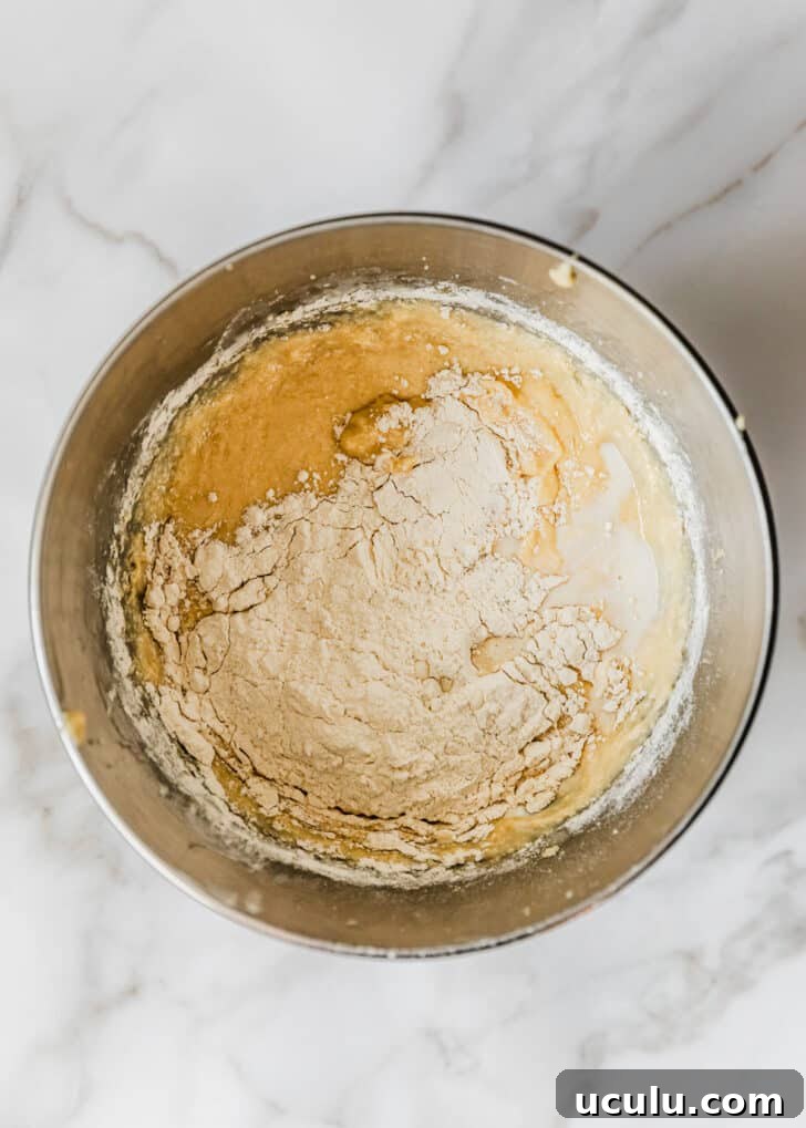 A silver bowl of batter and flour on a white counter.
