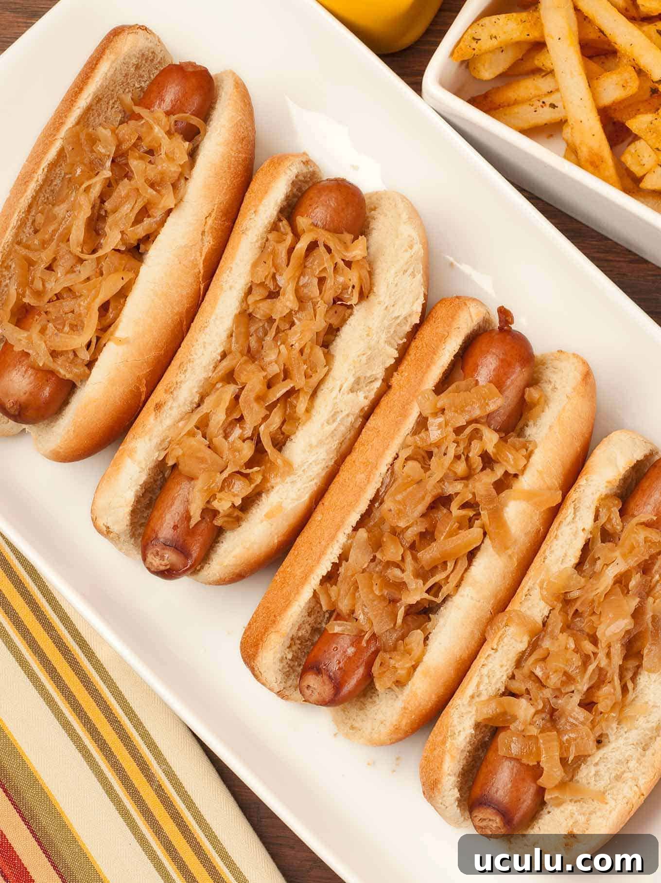 Hot dogs simmered in beer in buns topped with sauerkraut and served with seasoned French fries.