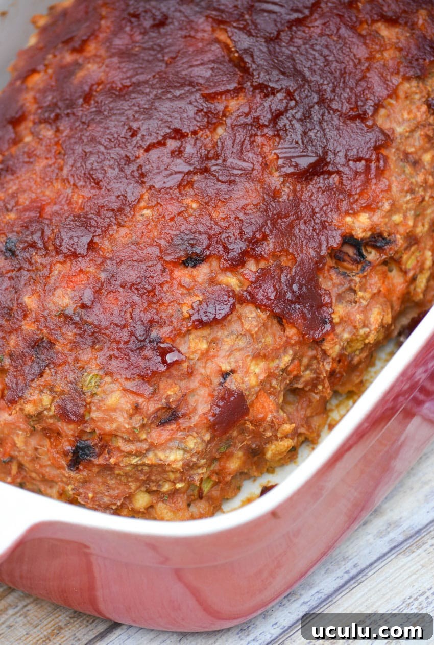 a baked, cranberry sauce topped turkey meatloaf in a red casserole dish