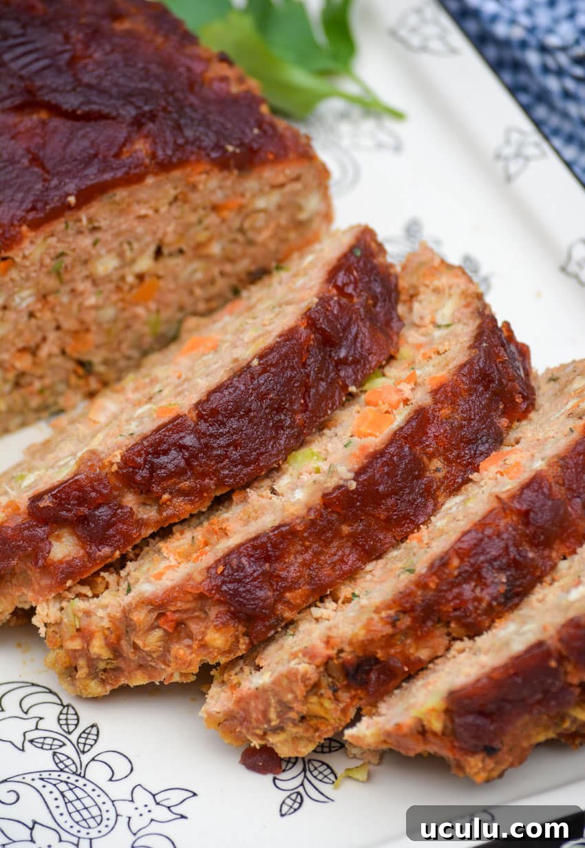 slices of cranberry sauce topped turkey meatloaf on a black and white serving platter