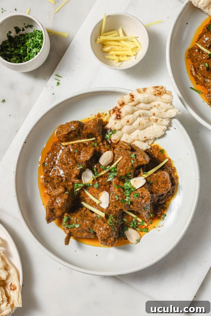 Lamb Korma on a plate garnished with blanched almonds, cilantro, and julienned ginger
