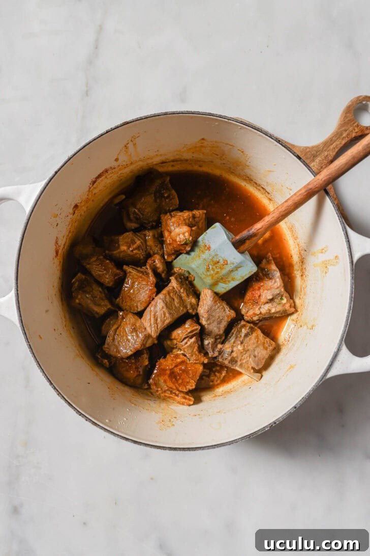 Sautéing ground spices and mutton in a pot to make Mutton Korma.