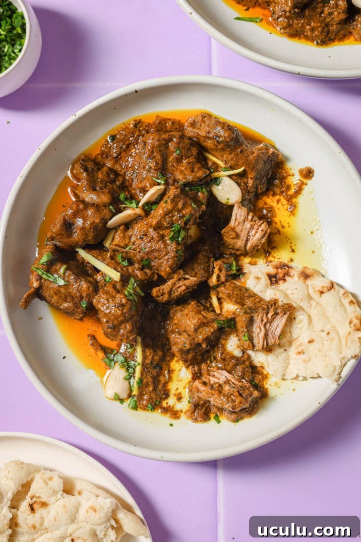 Partially eaten plate of Mutton Korma with a piece of naan on the side.