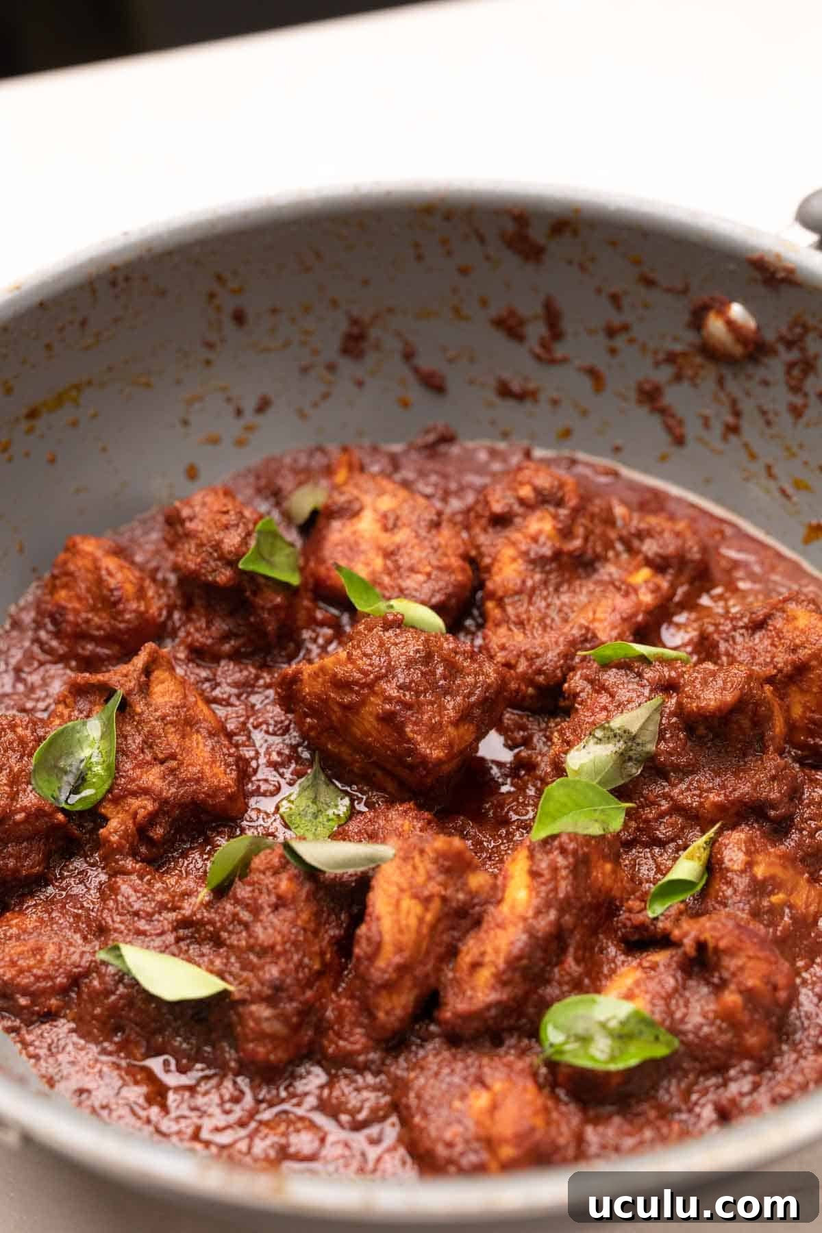 chicken ghee roast being cooked in a grey pan
