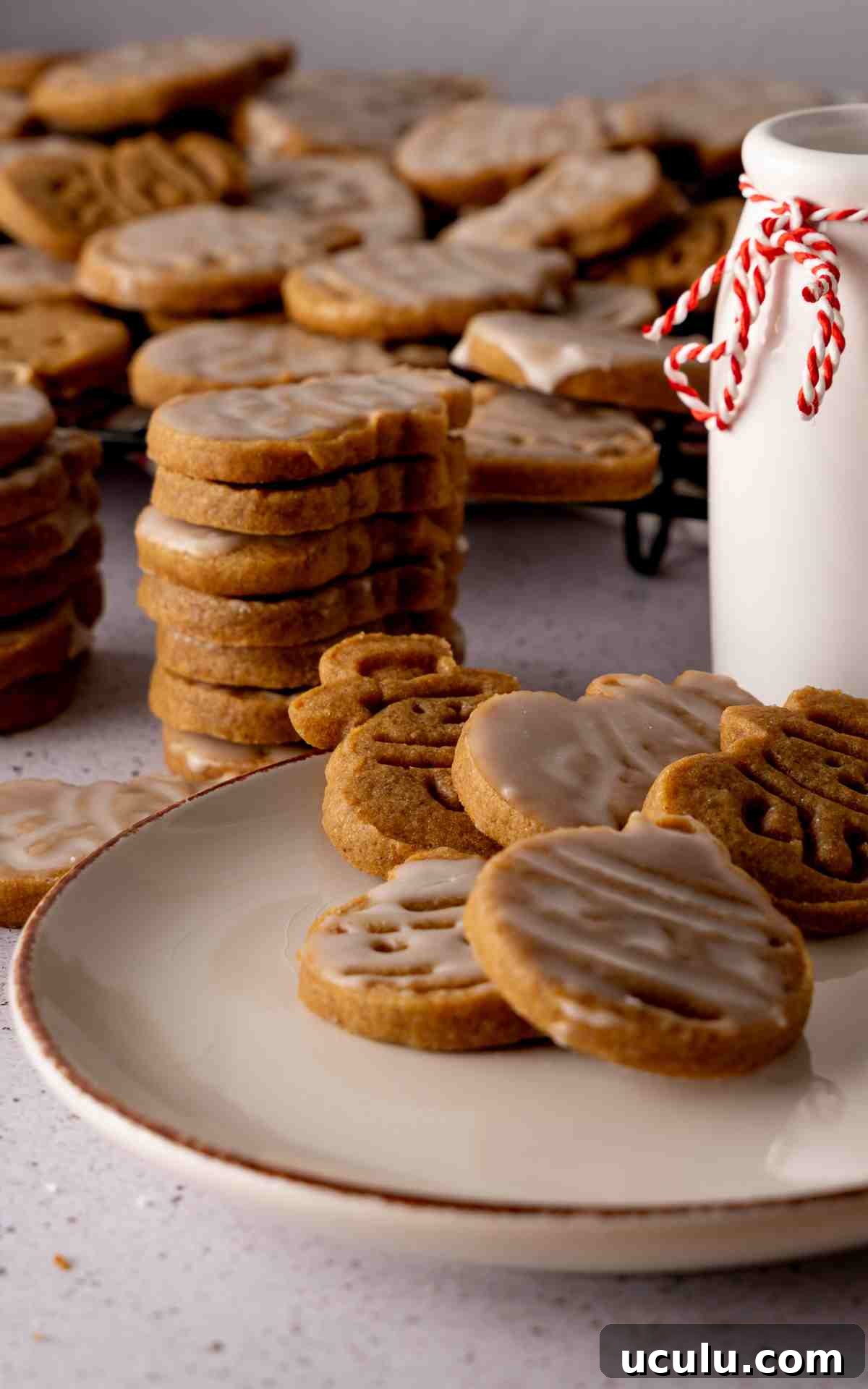 A plate of cutout cookies with vanilla glaze and a glass of milk.