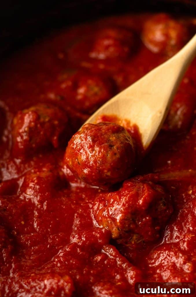 gluten free meatballs in a slow cooker with a wooden spoon