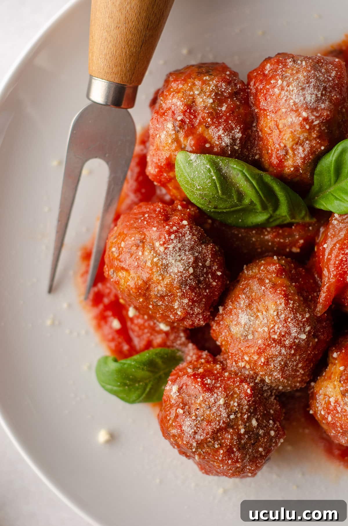 aerial photo of gluten free meatballs on a plate with basil leaves and a serving fork