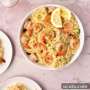 Large serving bowl with shrimp lemon pasta served with lemon wedges.