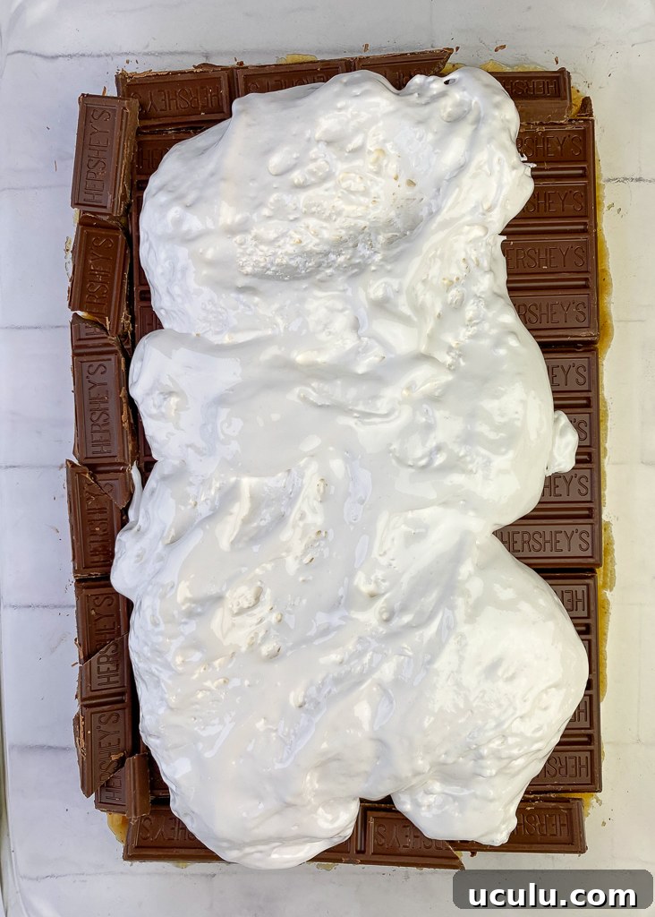 Large tub of marshmallow fluff poured onto the center of thick Hersheys chocolate bars on a cake