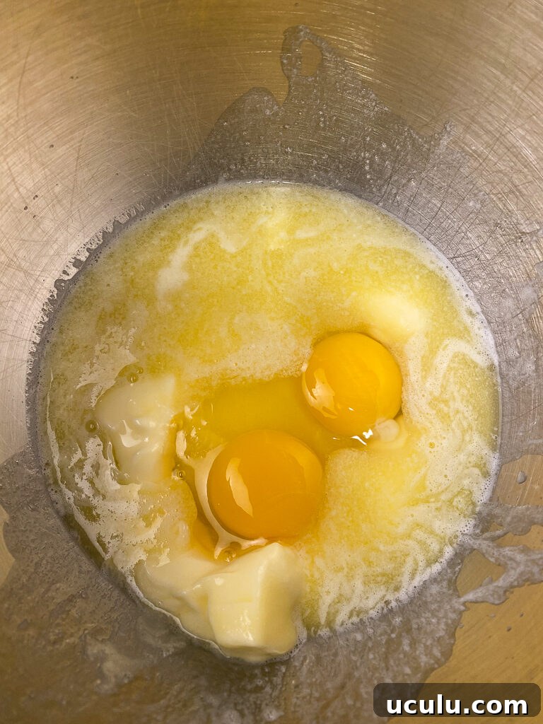 Eggs and melted butter in a silver mixing bowl