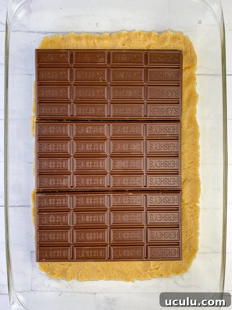 Chocolate bars centered on a graham cracker dough crust in a glass baking dish