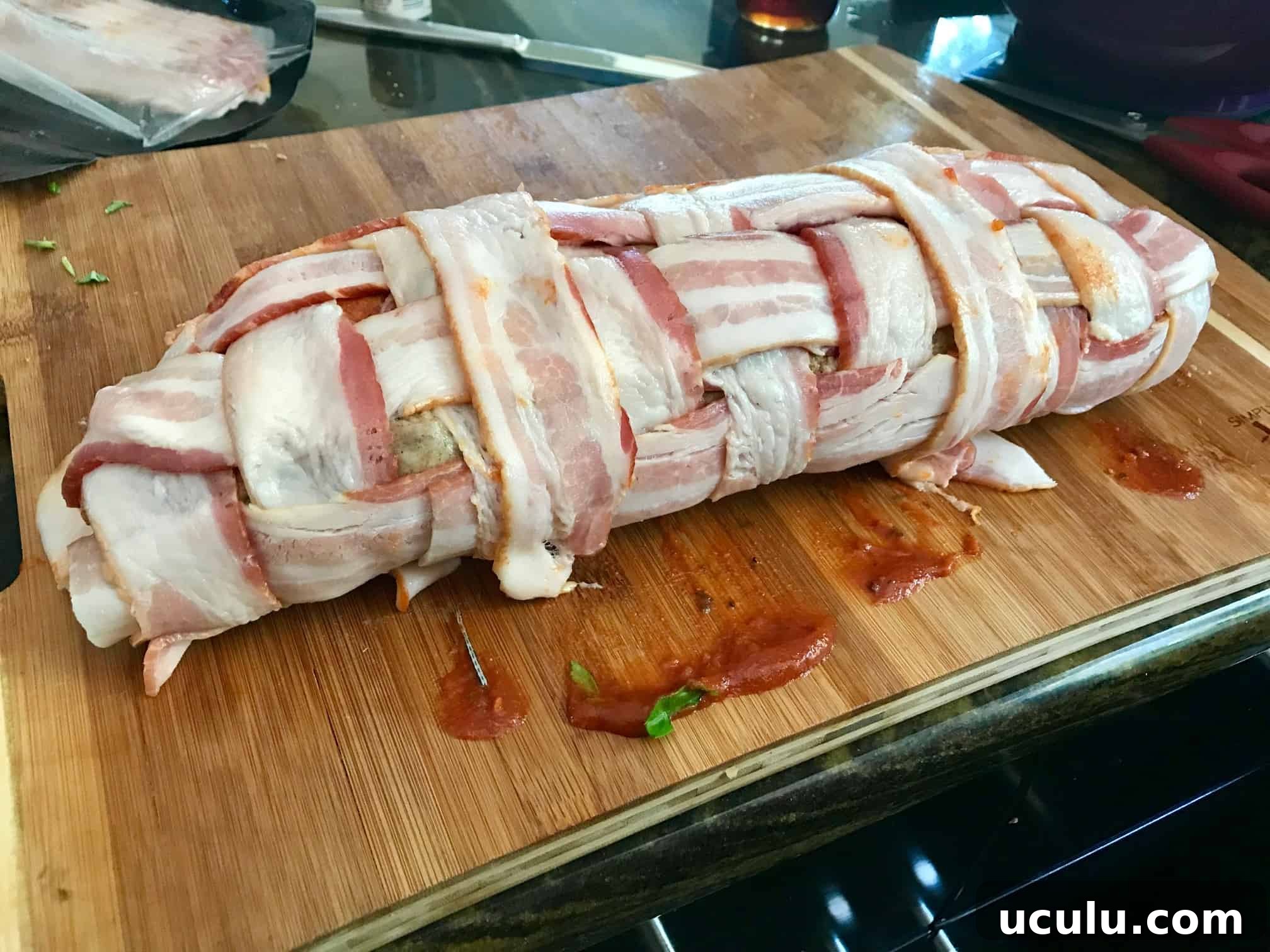 Pizza Bacon Explosion rolled up on wooden cutting board side view