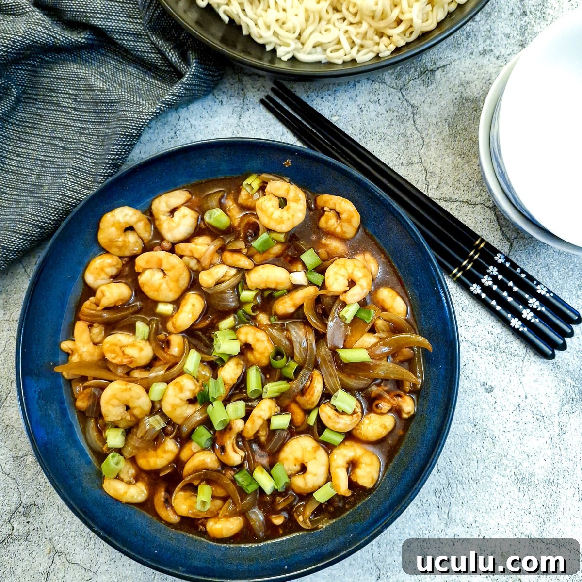 A dark blue serving dish filled with kung pao prawns and cashews.