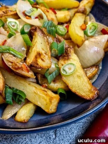 A plate of salt and pepper chips in a blue serving bowl next to a red chilli