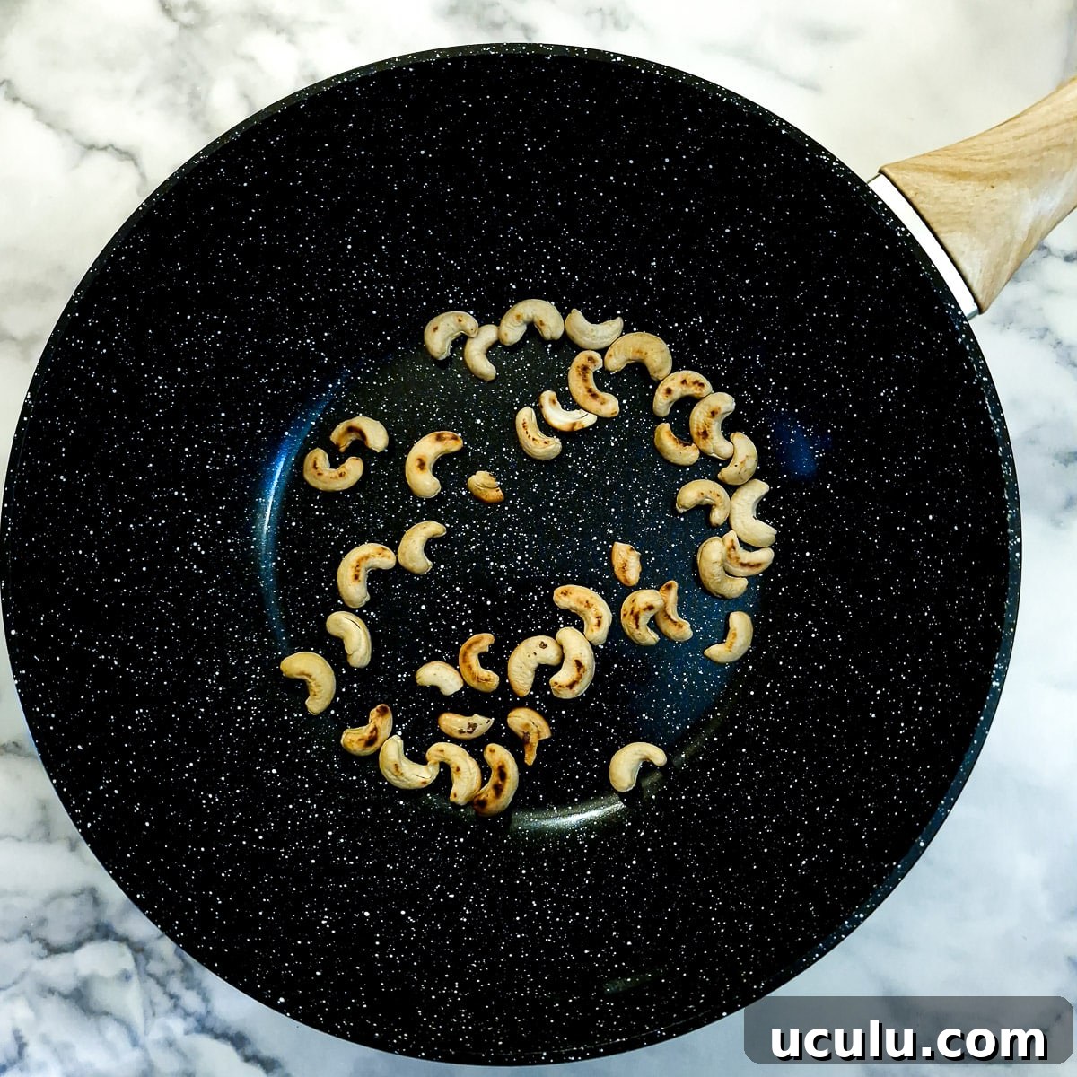 Cashew nuts toasting in a wok.