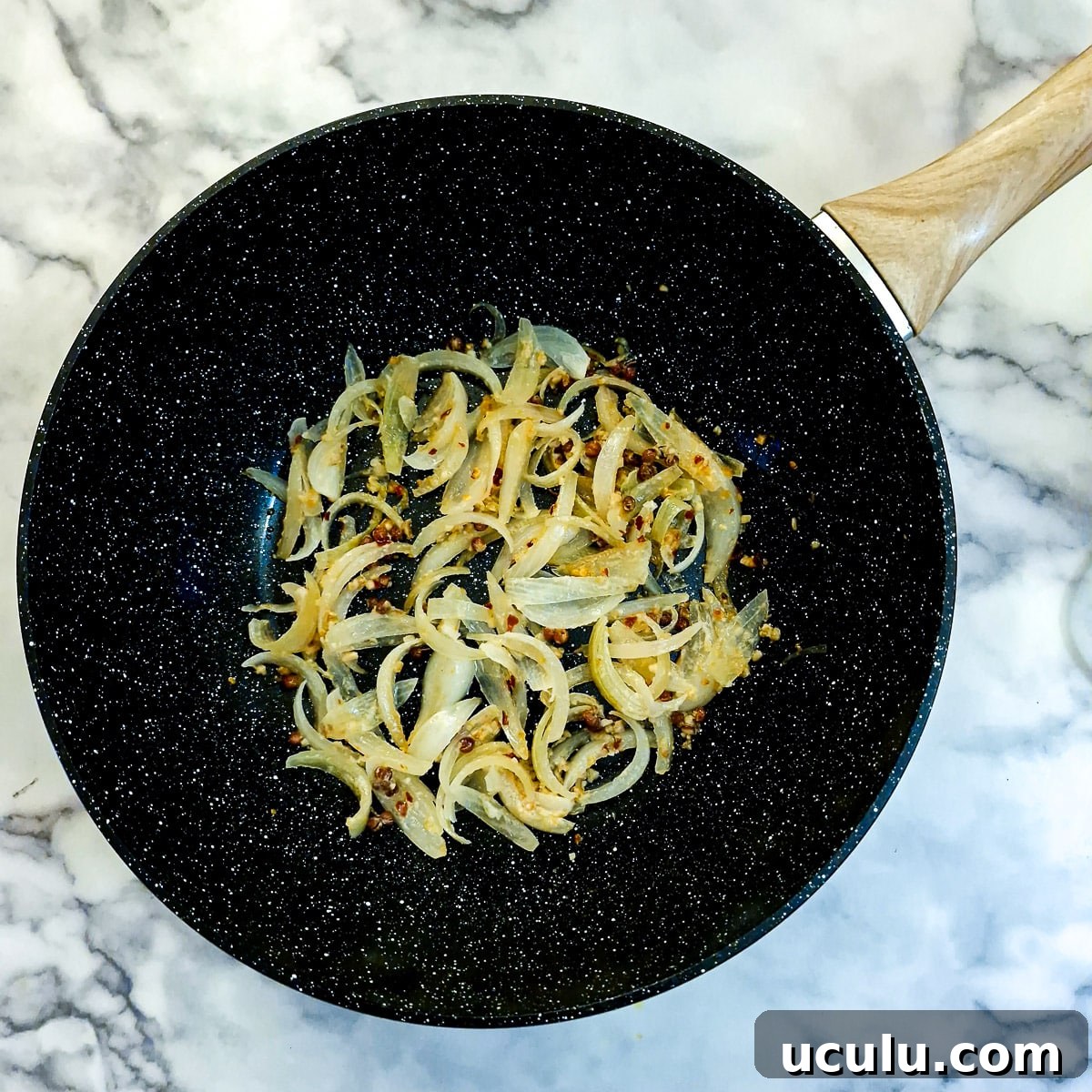 Sliced onions and spices frying in a wok.