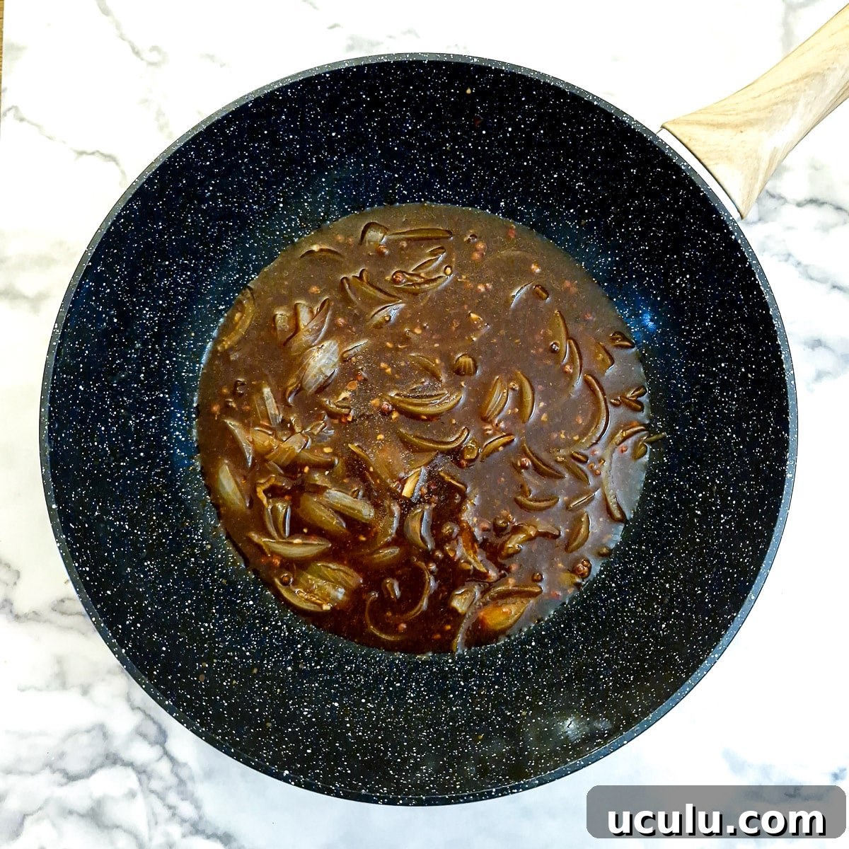 Sauce ingredients added to onions in a wok.