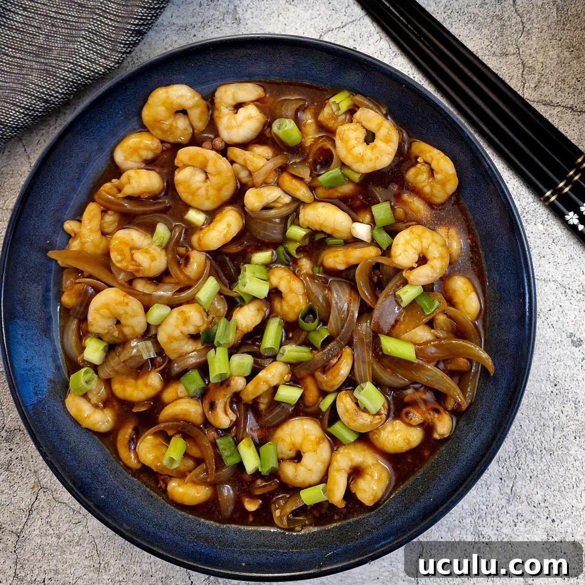 The finished dish of kung pao prawns garnished with chopped spring onions.