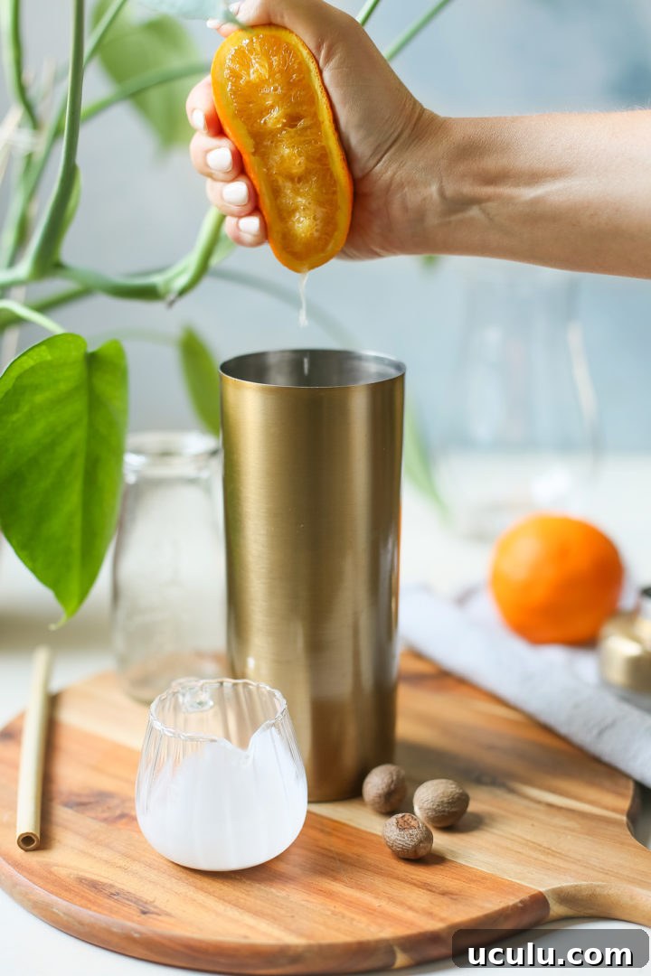 woman squeezing orange juice into a cocktail shaker