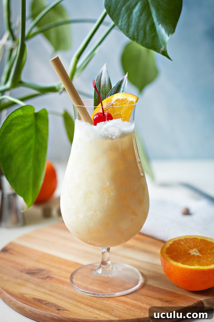 painkiller cocktail in a glass garnished with orange and cherry