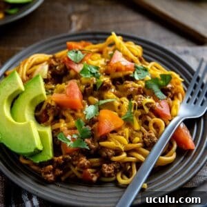 Mexican Spaghetti on brown plate with sliced avocado on the side.