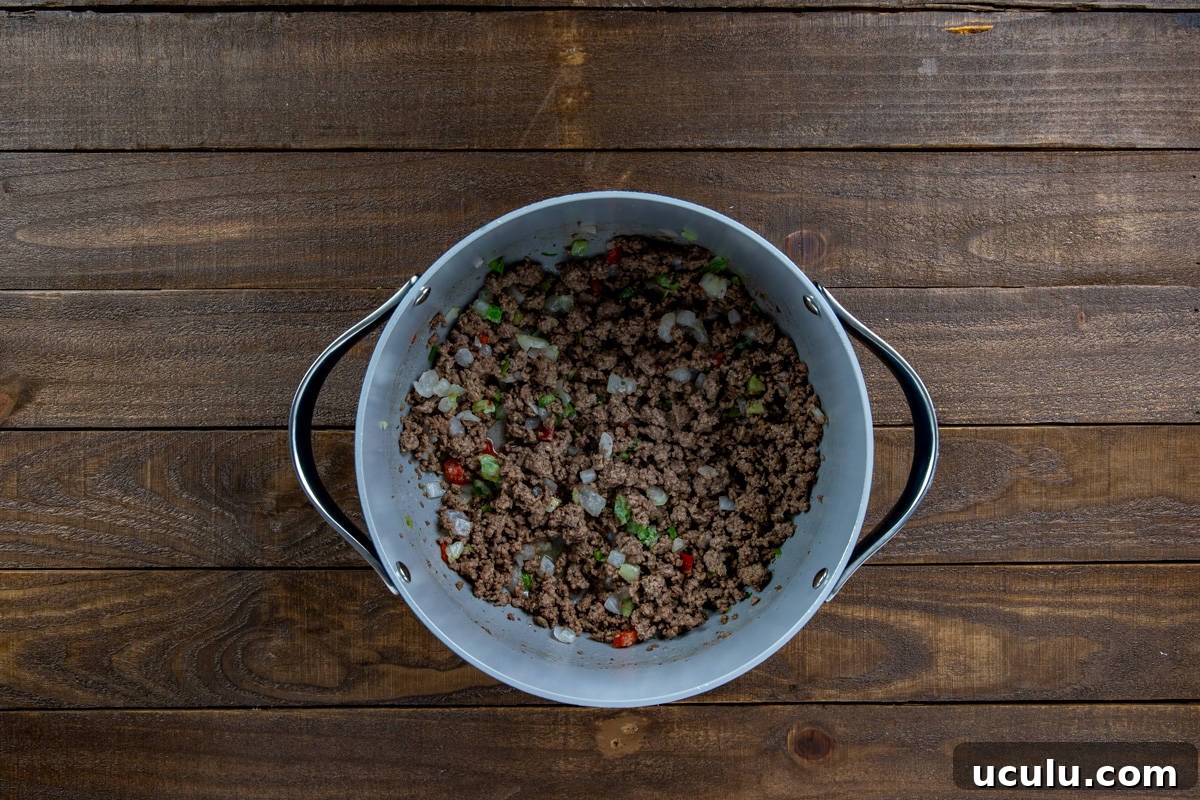Chopped onion, bell pepper, and celery cooked in the pan with the ground beef.