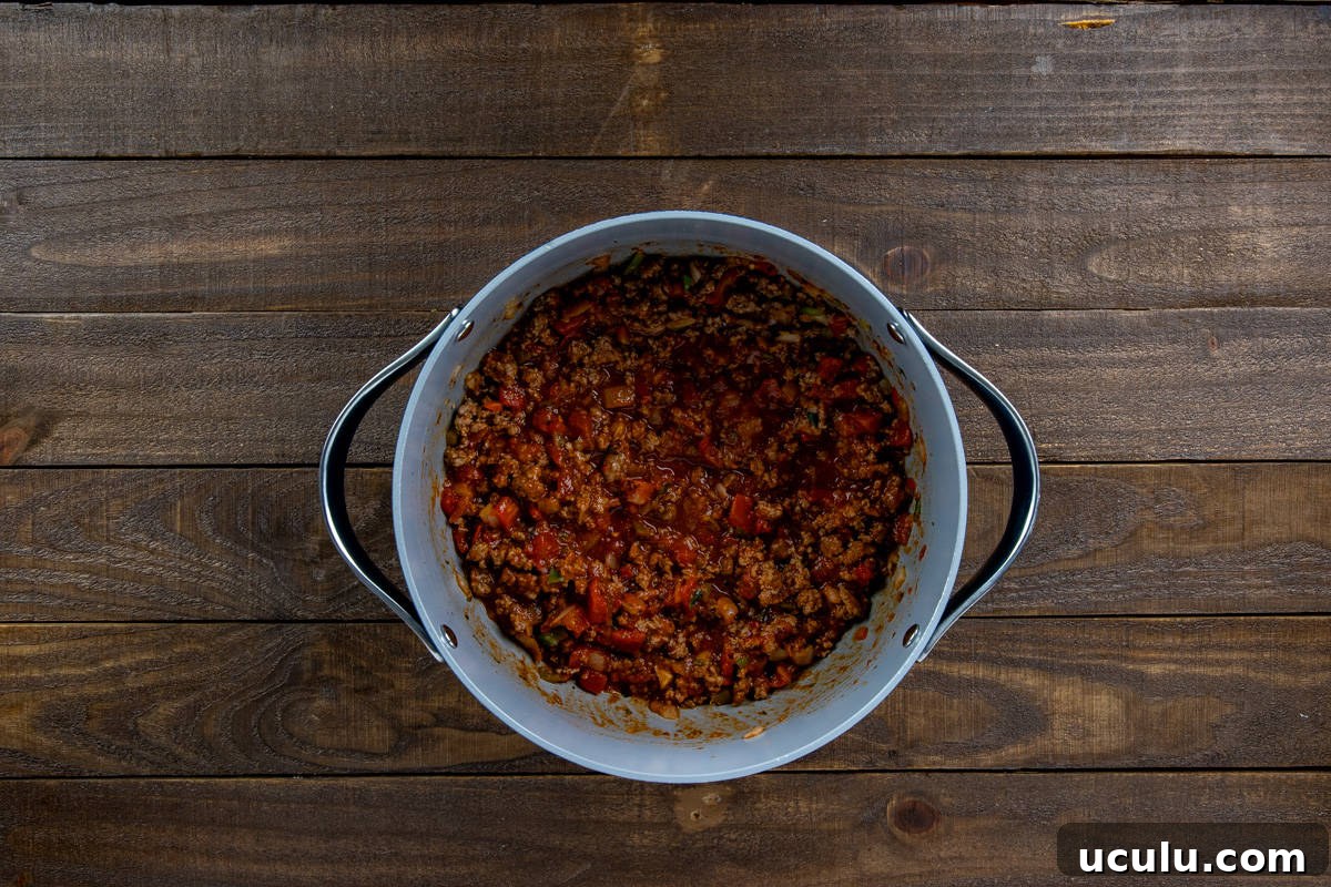 Rotel tomatoes, tomato sauce, tomato paste, taco seasoning mix, sugar, and parsley flakes added to the pan.