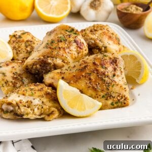 A plate of Baked Chicken Thighs with lemon slices.