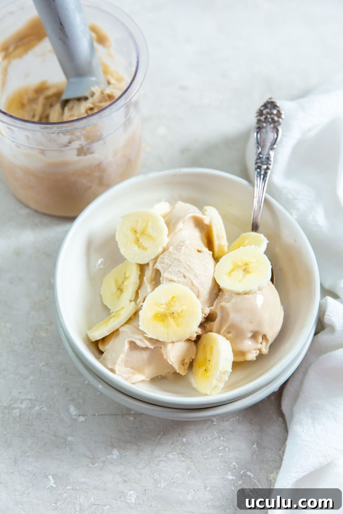 Ninja Creami Banana Ice Cream in a white bowl with sliced bananas on top