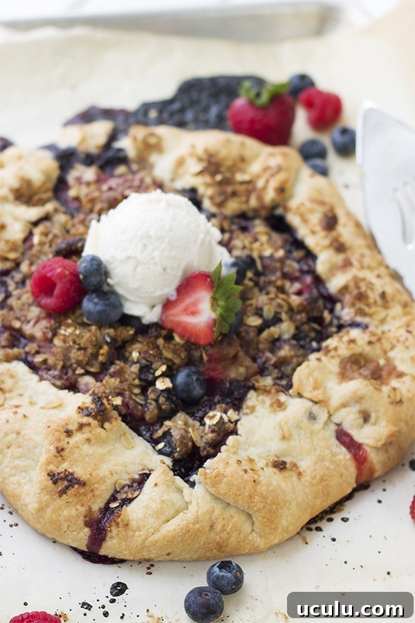 a berry galette on a baking sheet with fresh berries and vanilla ice cream on top 