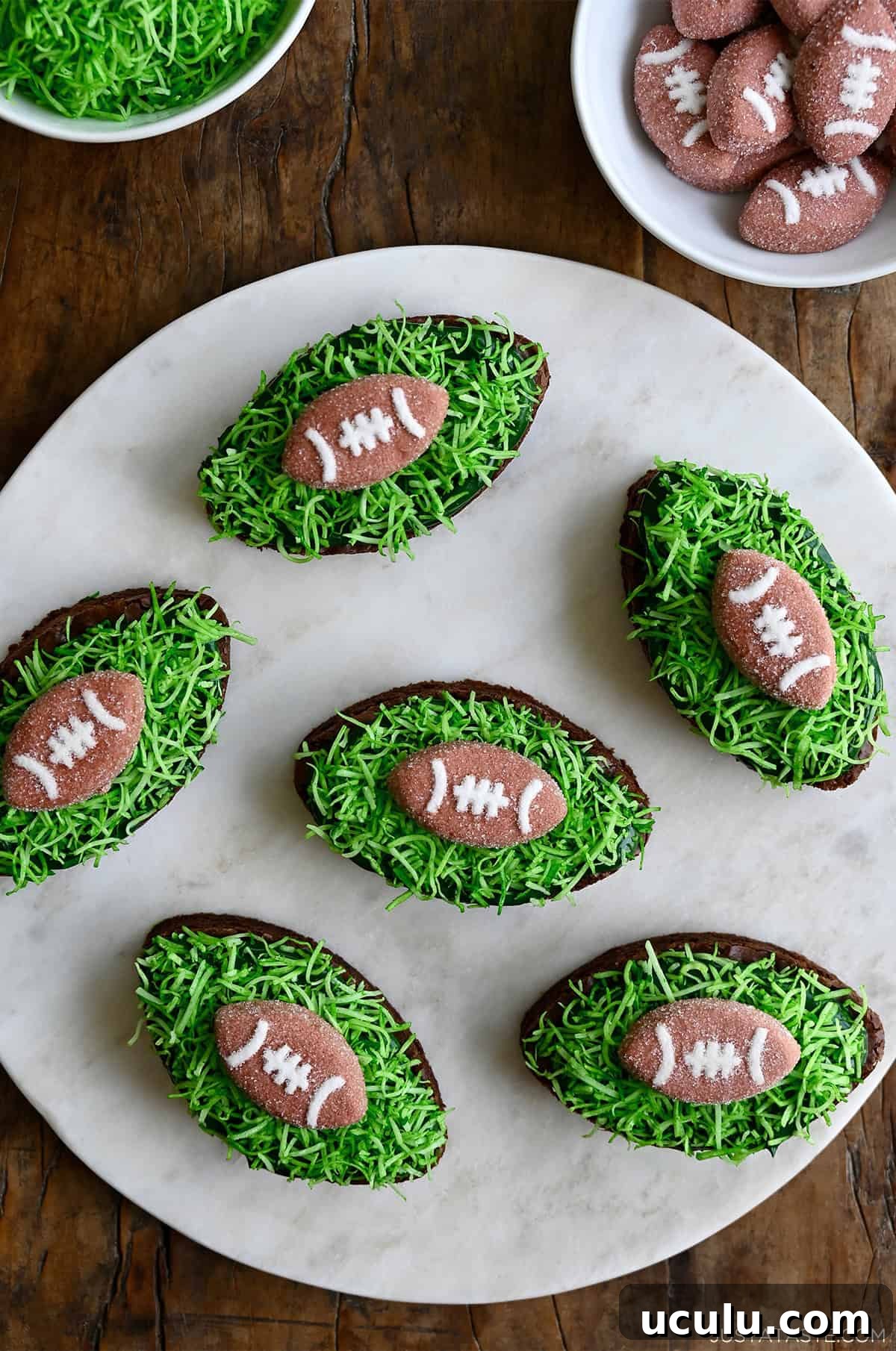 Football-shaped brownies topped with green frosting and football marshmallows.