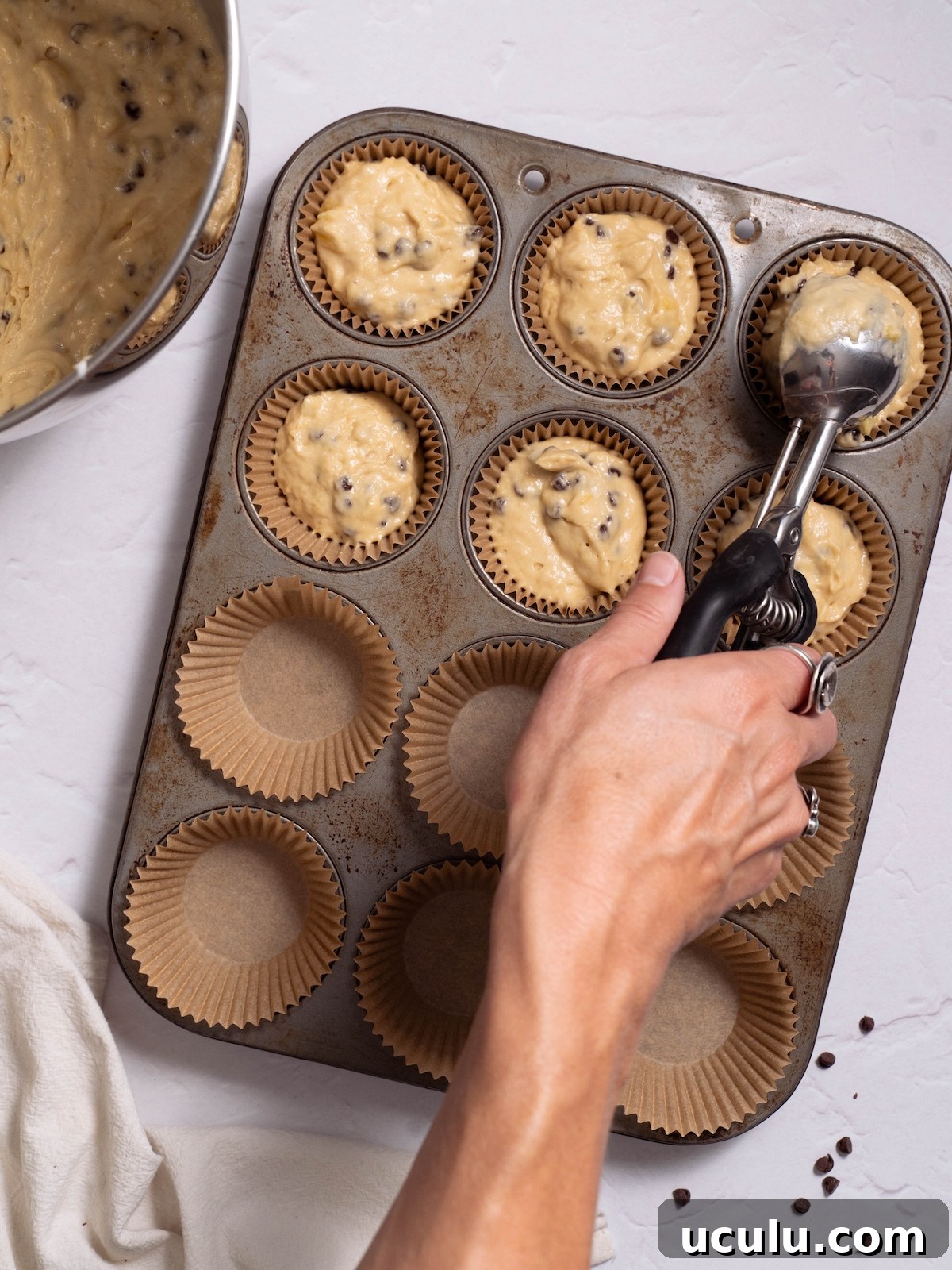 Scooping muffin batter into a lined muffin pan