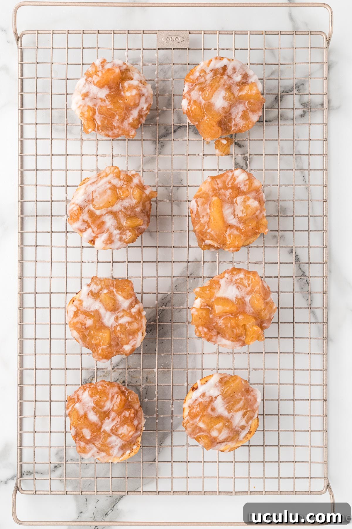 Apple pie cups topped with glaze on wire rack.