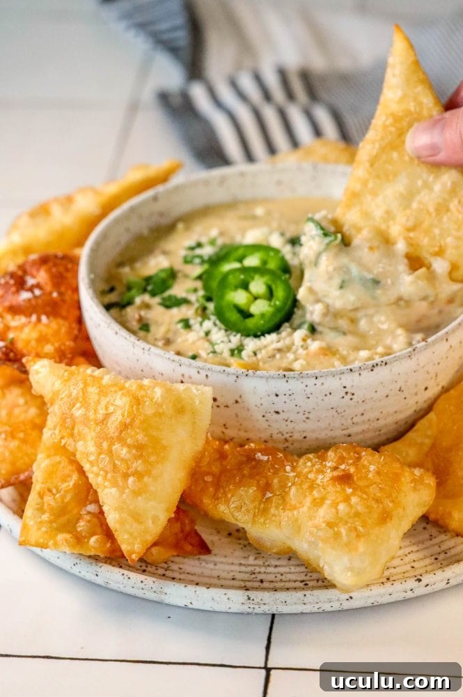 white queso with jalapenos, cilantro, and chips being dipped in it