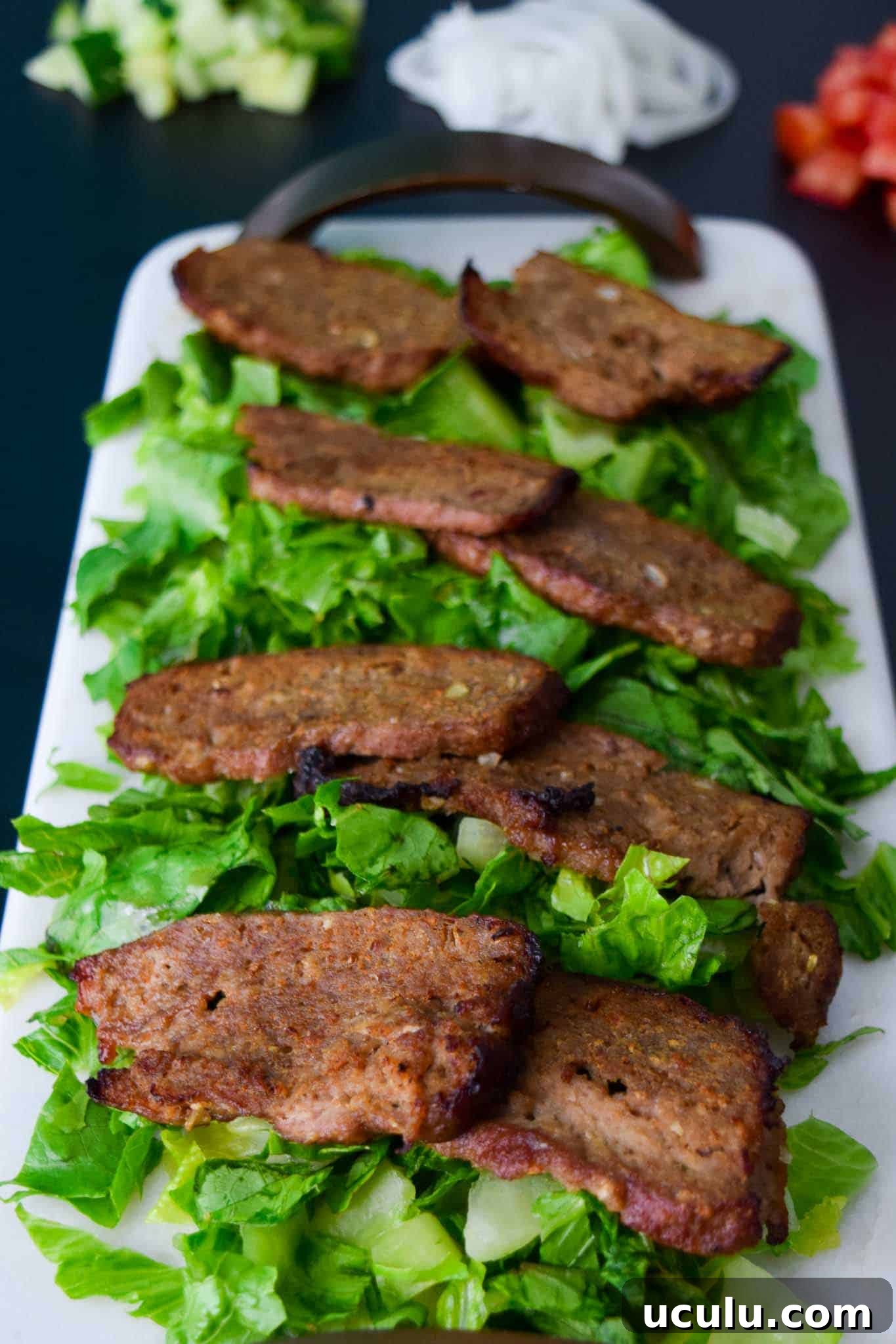 Gyro Meat sliced on bed of lettuce on white platter
