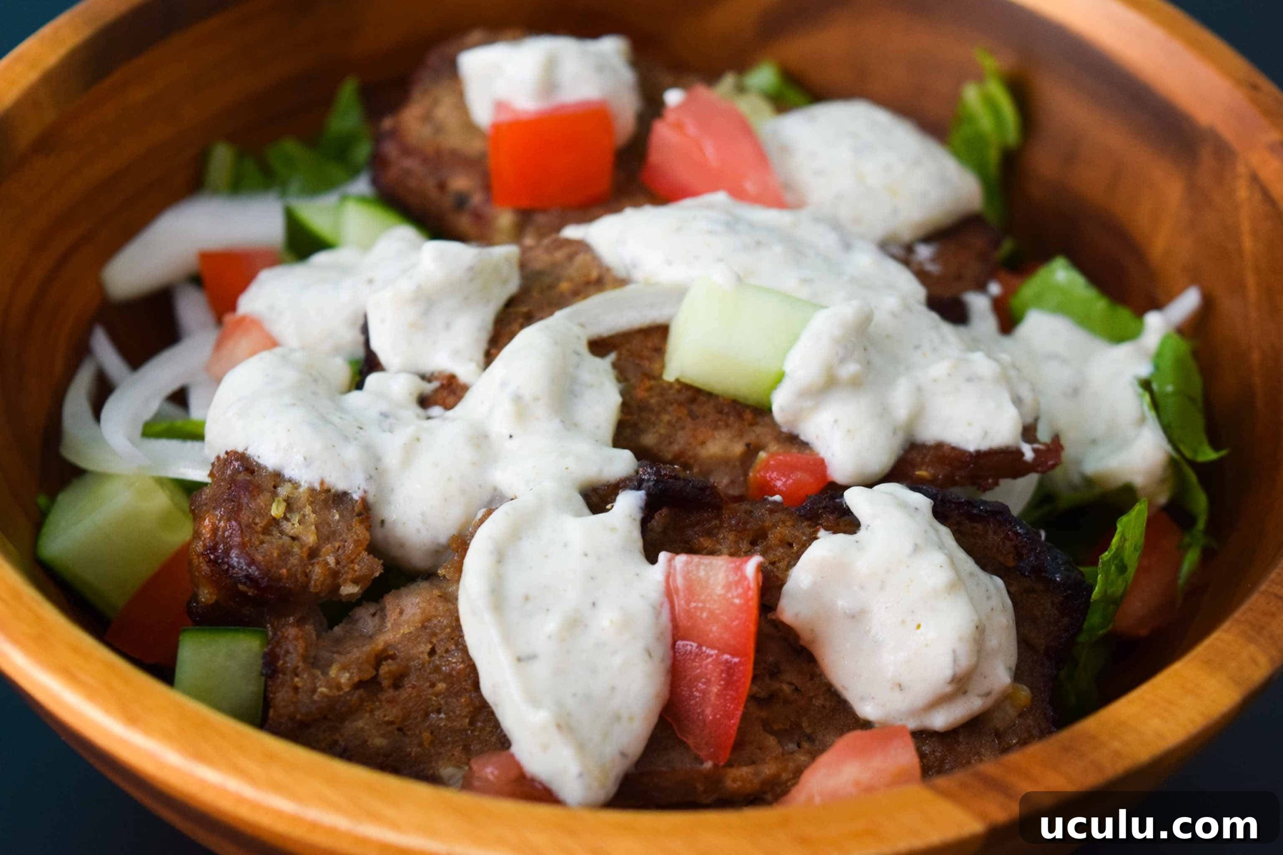 Gyro Meat in salad bowl close up topped with tzatziki 