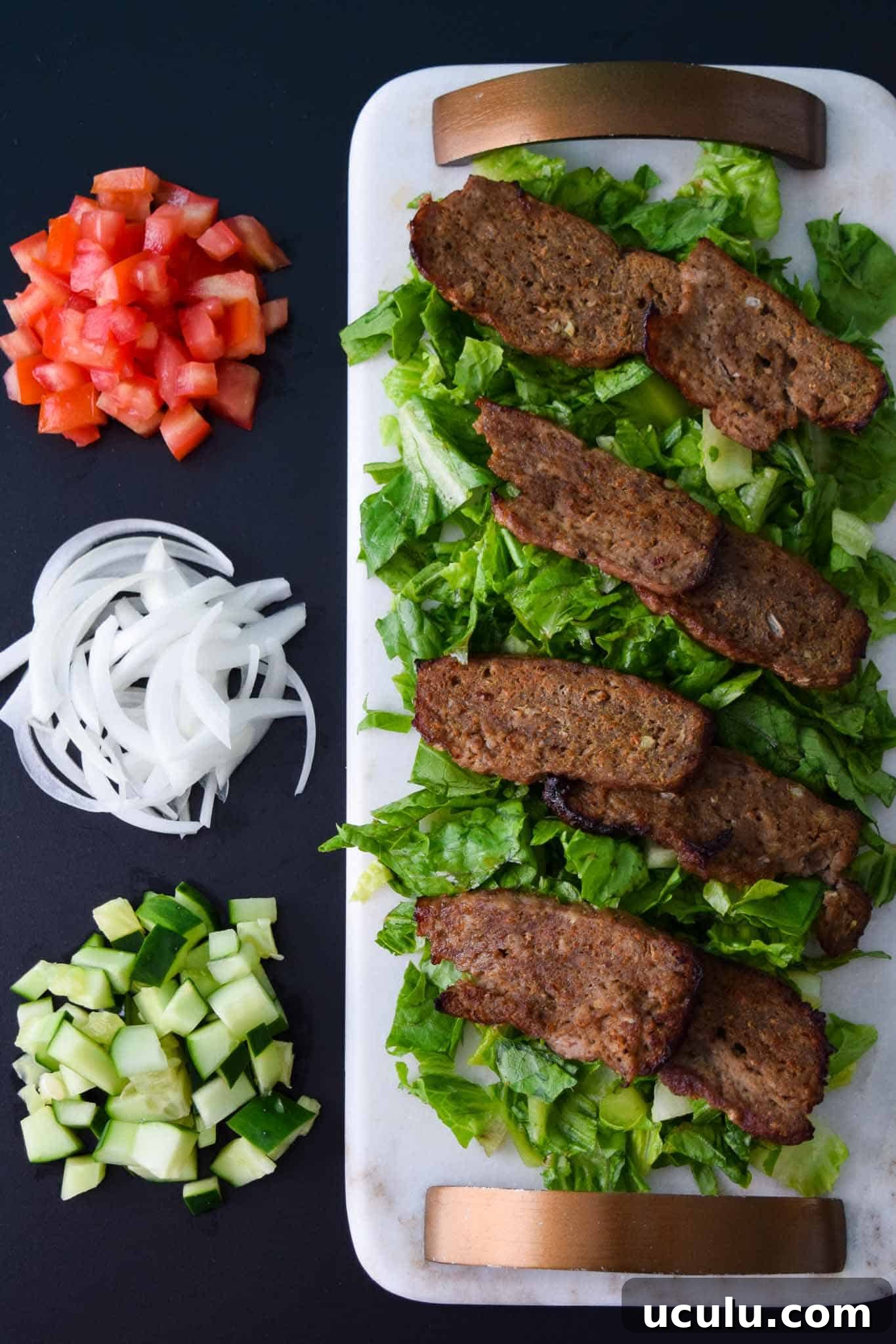 Gyro Meat on white platter with toppings beside it overhead shot