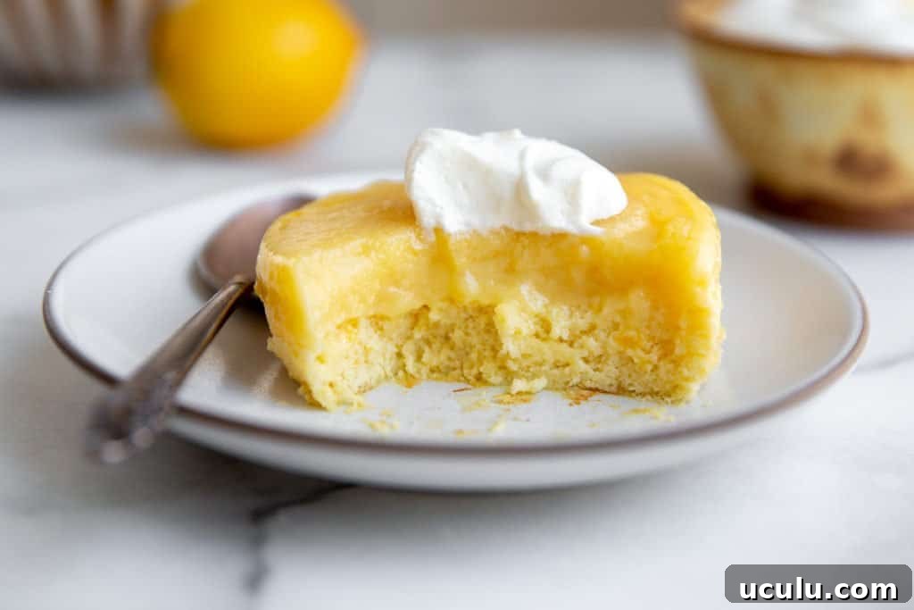 An inverted lemon pudding cake on a plate with a bite taken out.