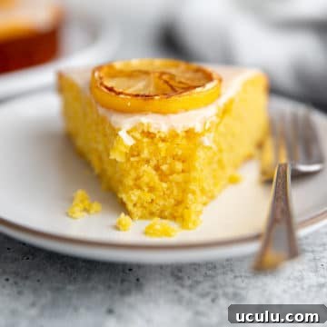 A slice of lemon olive oil polenta cake on a plate with a fork.