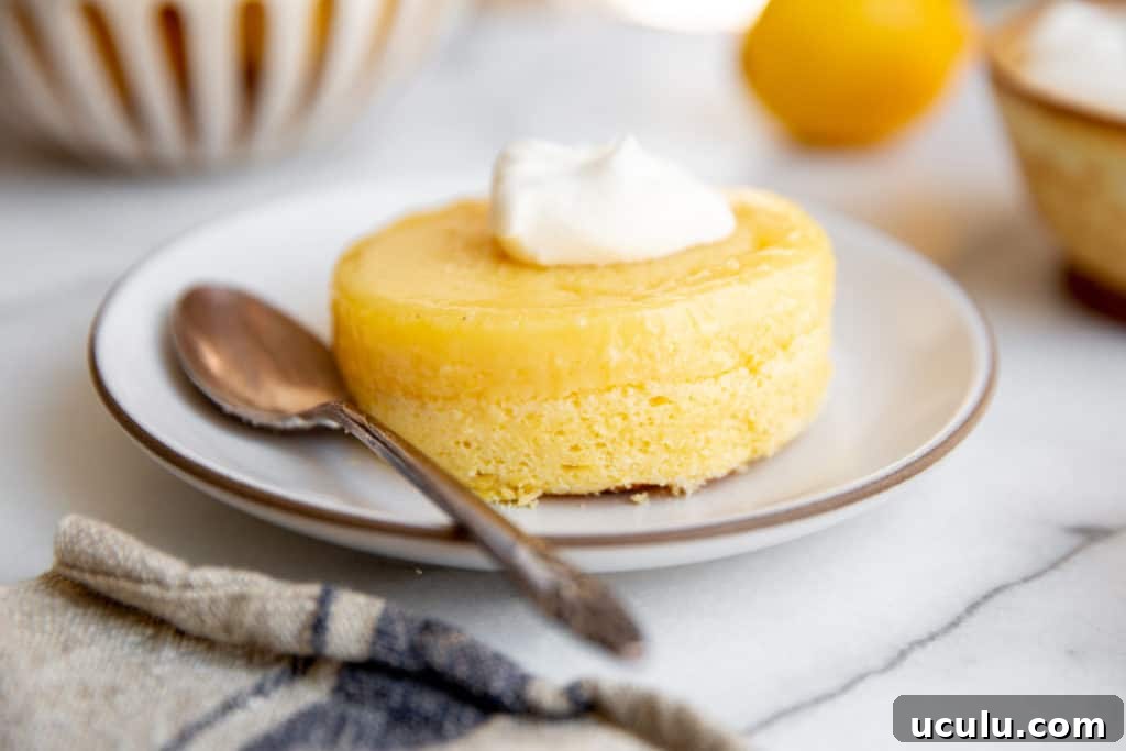 A lemon pudding cake inverted onto a plate, topped with whipped cream.