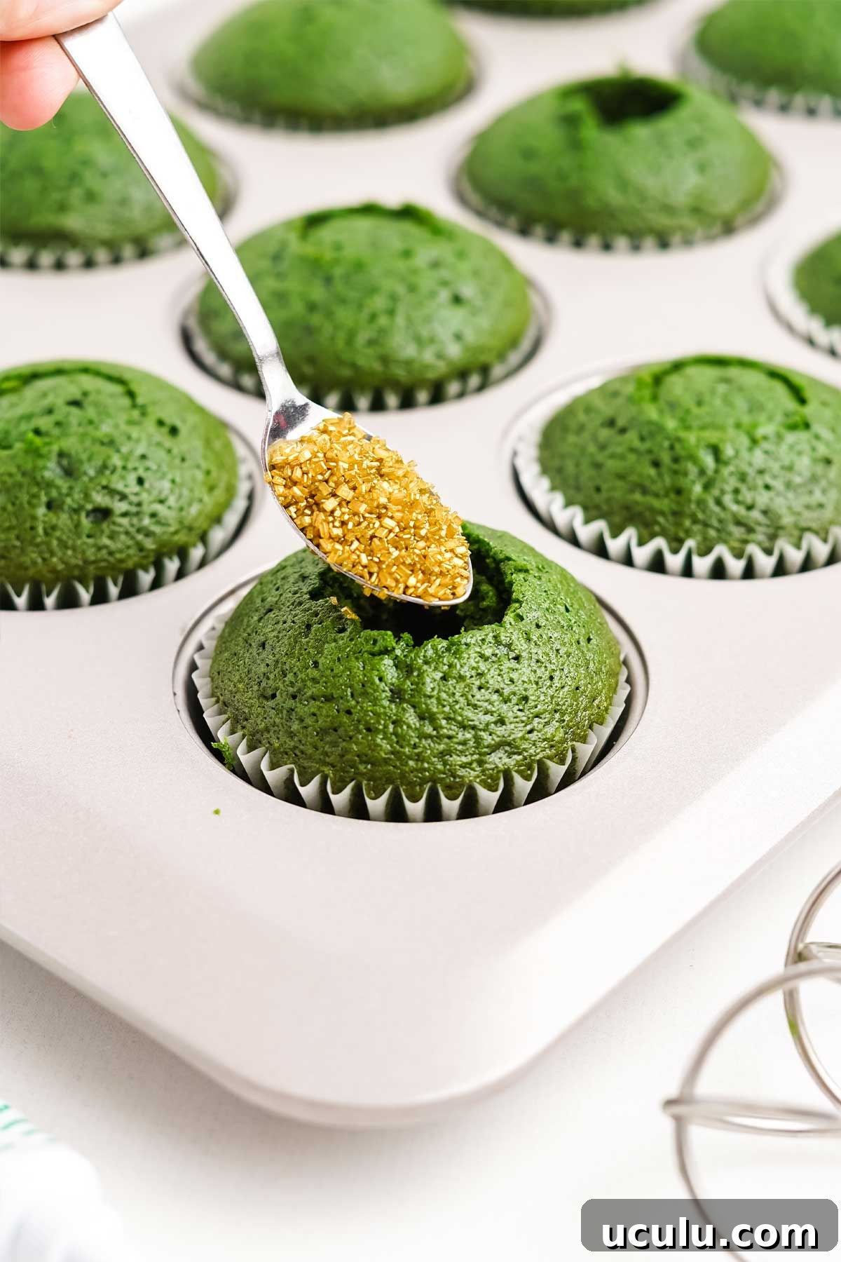 Filling the hole in the cupcake with gold sprinkles.